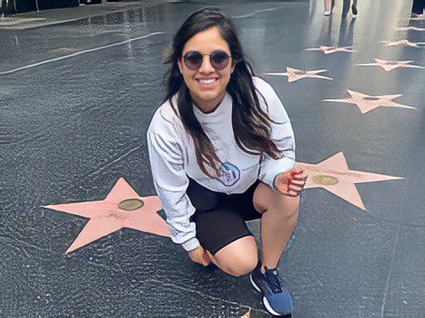 young woman kneels for photo on Hollywood Walk of Fame